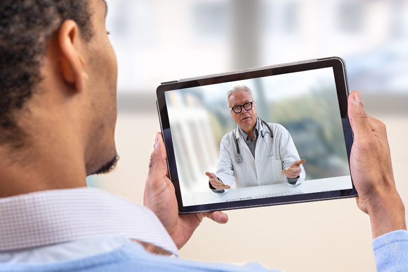 Telemedicine and health care concept with a young man and a doctor on computer screen