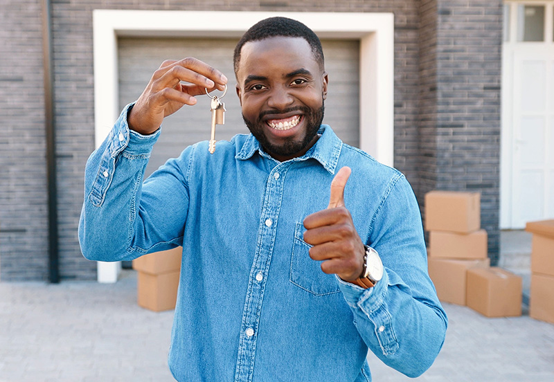 Portrait of cheerful happy African American man smiling to camera and showing key.
