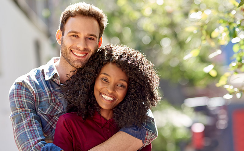 Neurodiverse adult couple affectionately standing together outside on a sunny day