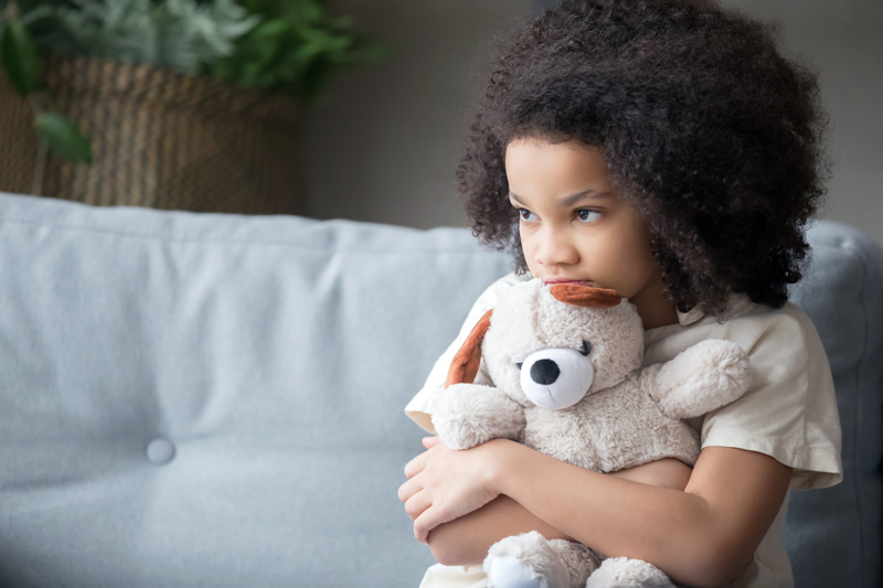 lonely young girl holding teddy bear looking away