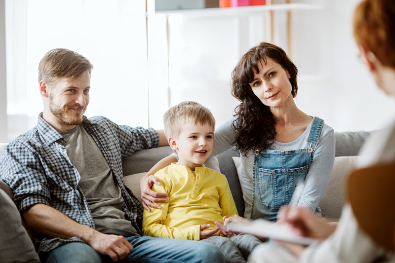 Caring parents with their son at a therapy session with counselor