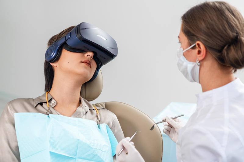 A dentist examines her patient while the patient is wearing a virtual reality headset