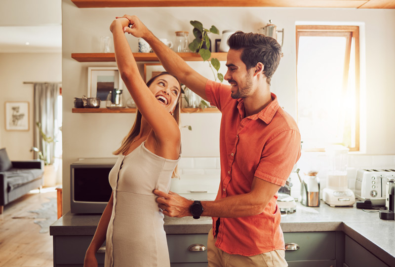 A joyful, dancing, and loving neurodiverse couple bonding and having fun in the kitchen together at home.