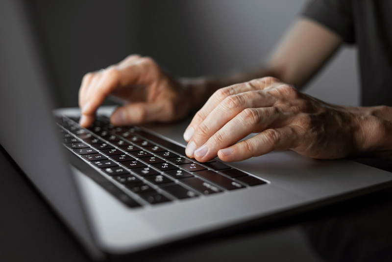 man's hands typing on a laptop computer