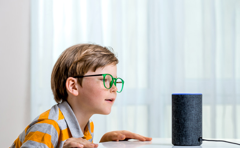 Young boy talking to talking to Amazon Alexa smart technology device