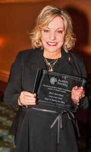 Linda J. Walder holding the 2023 Daniel Jordan Fiddle Foundation Leader in Adult Autism Award