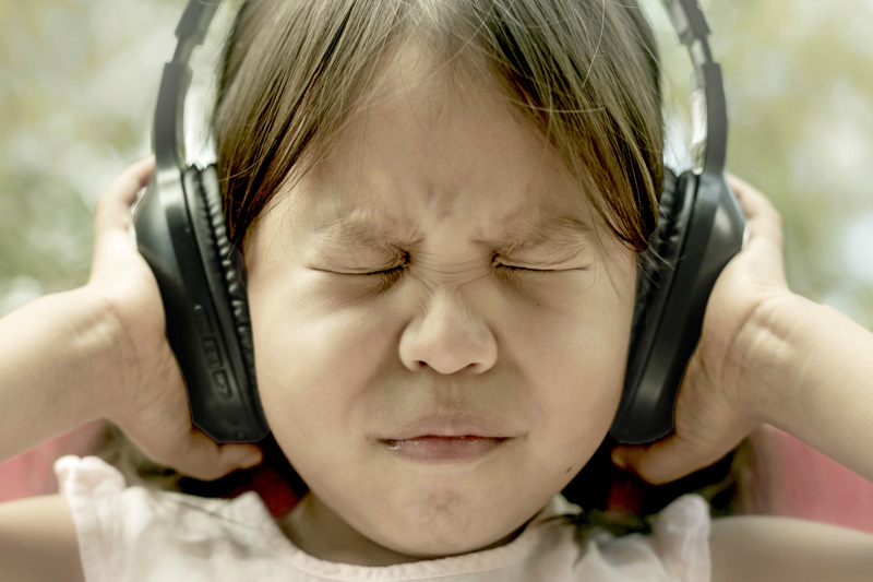 Child covering noise canceling headphones for sensory processing