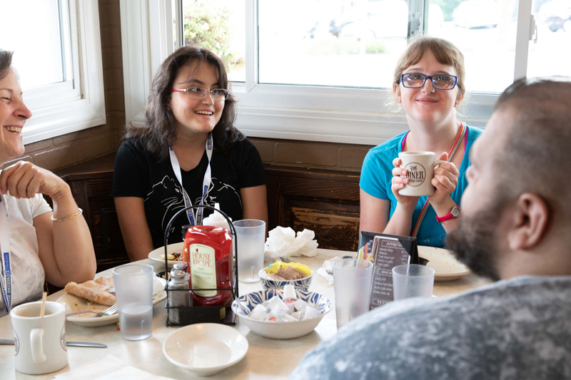 A group of Perkins School for the Blind teenagers and adults enjoying lunch at a restaurant