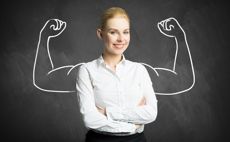 Woman in white shirt smiling in front of a drawing of muscled arms