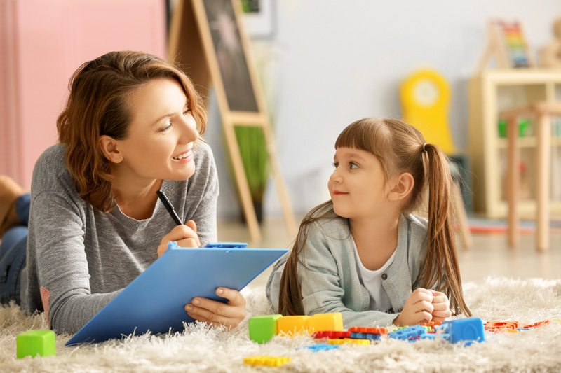 Female psychologist with little girl during play therapy