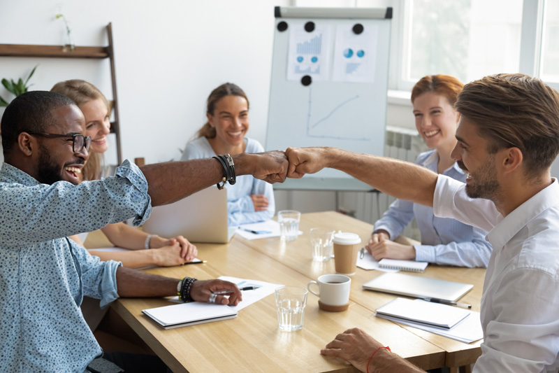 Coworkers fist bumping congratulating each other with success at work