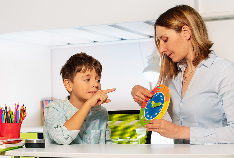 Autistic boy and teacher learn clock together during Applied Behavior Analysis