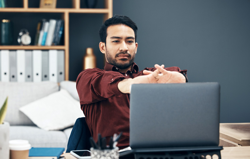 Man taking a break at work to stretch his arms and fingers