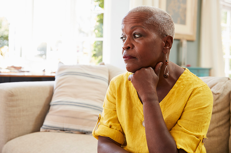 Senior Woman Sitting On Sofa At Home Suffering From Depression