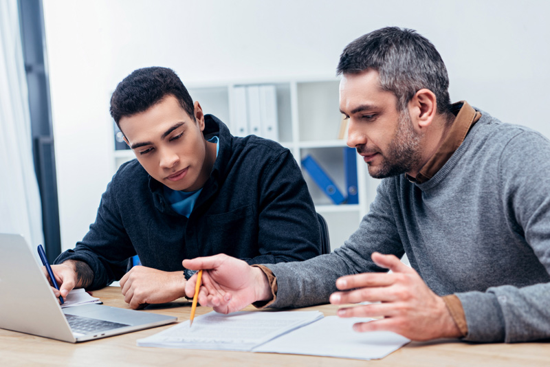 concentrated male coworkers working with papers and laptop in office