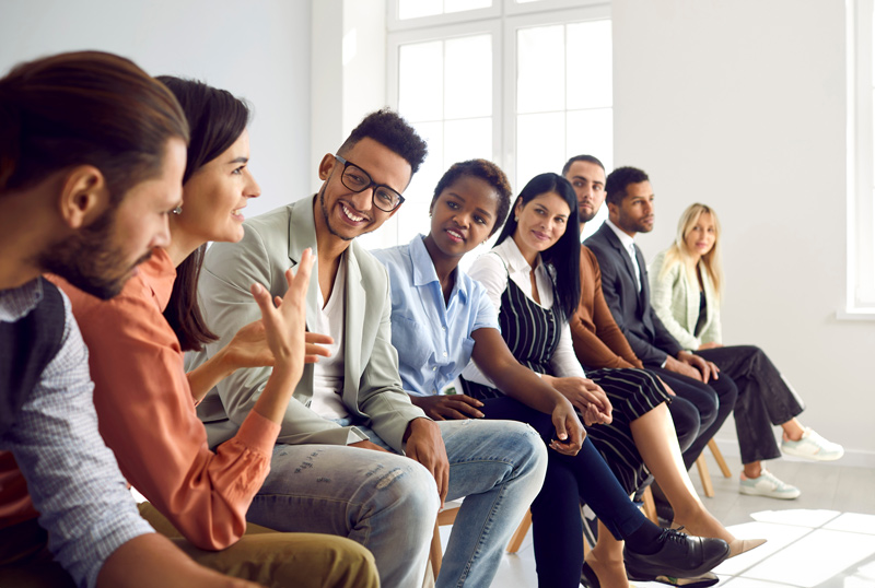 Diverse group of happy young people having discussion during business meeting or training