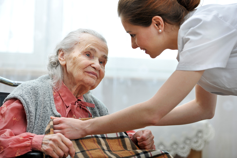 Young woman covering elderly woman with a blanket