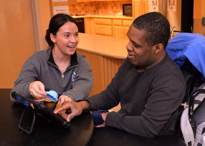 Darius using his AAC device to communicate with staff for communication access