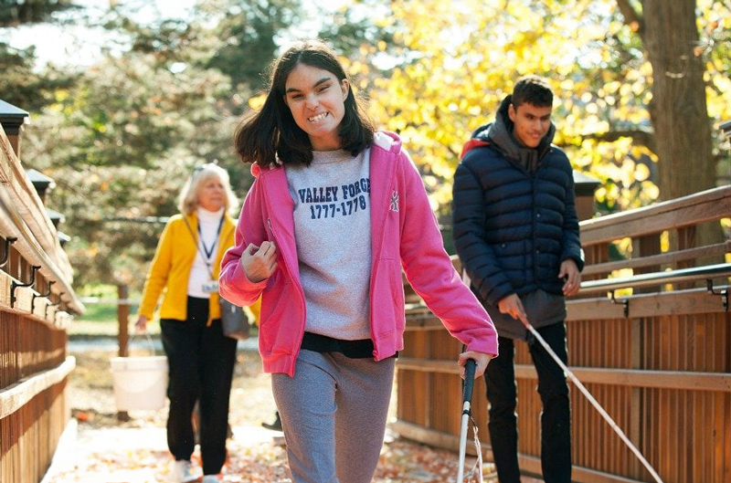 A young woman uses a white cane to navigate campus independently