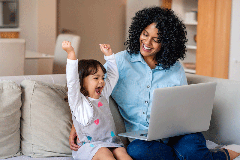 Laughing little girl and mother watching something on a laptop for ESDM-based caregiver coaching program