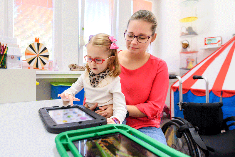 Non-verbal girl living with cerebral palsy, learning to use digital tablet device to communicate.