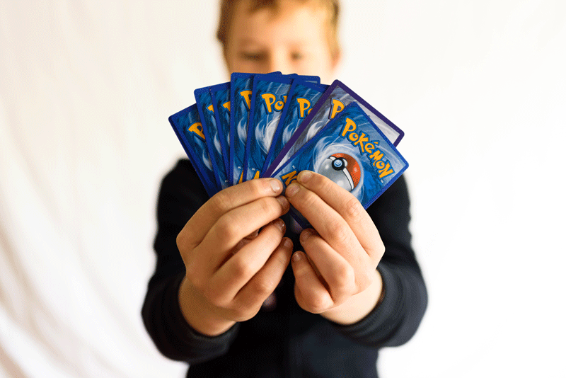 A single boy male hand holds a pokemon trading card game.