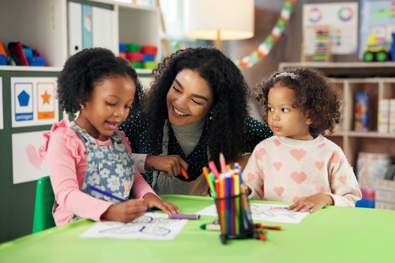 Drawing, learning and teacher with children in classroom for education, nursery and creative art. Growth, kindergarten and academy with woman and kids at school for helping and child development