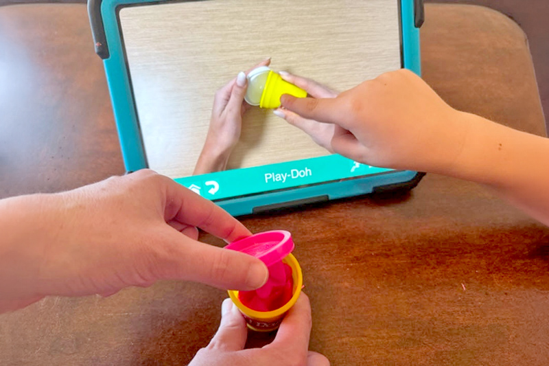 Example of a visual scene display being used to communicate "Open the Play-Doh”