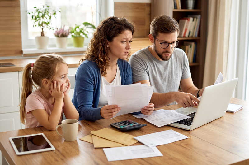 Parents Reviewing Bills with Daughter Looking On